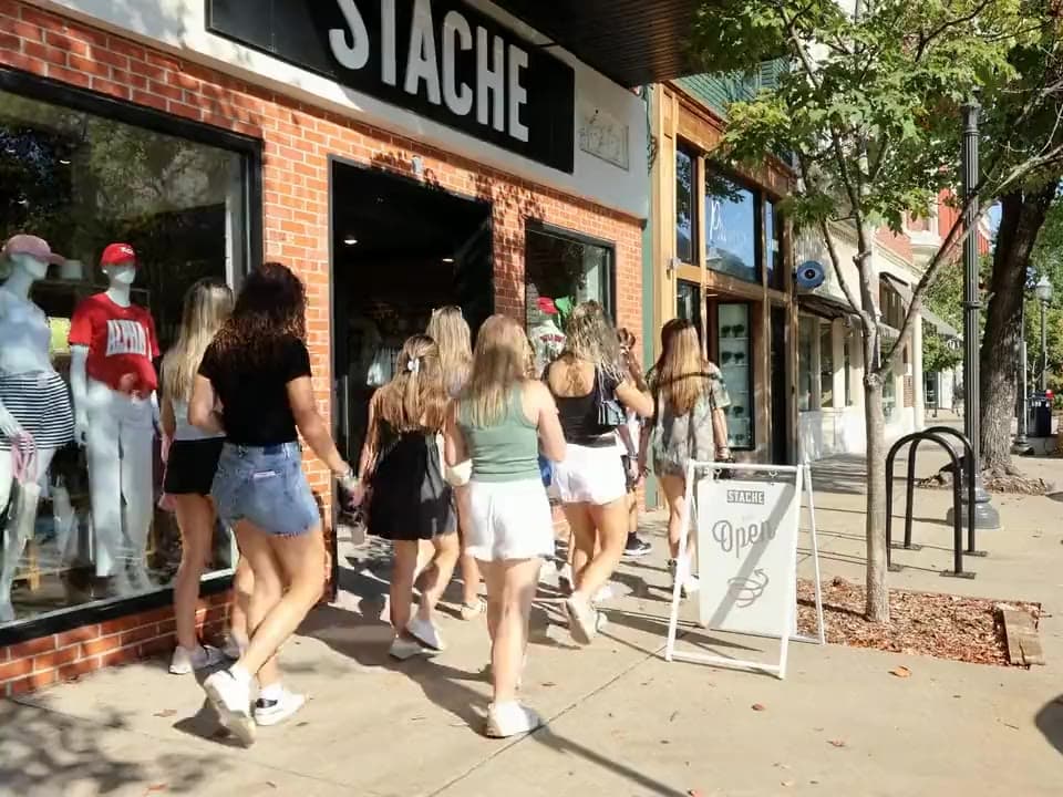 Shots from three films: a College Town Tours group walking past storefronts downtown, a new kitchen under woven pendant lights, Community Funded Solutions' founder speaking to camera, and the tour group at the Favoriteville mural.